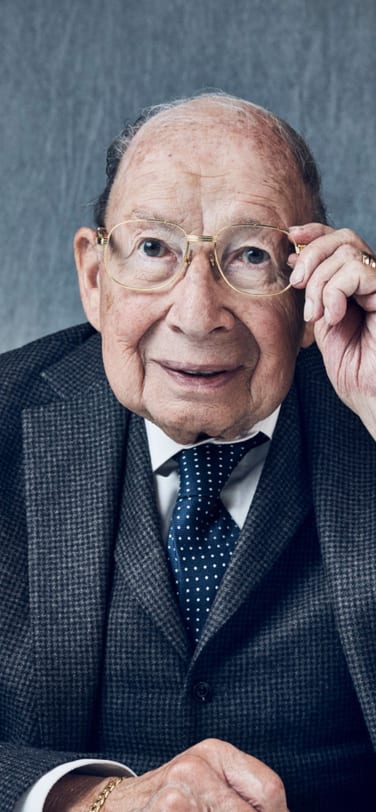 Kurt Klaus, the inventor of Perpetual calendar mechanism, sitting at the table against grey background