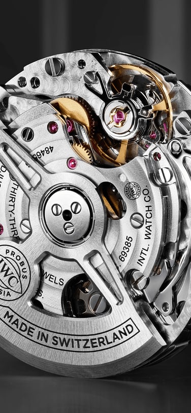 A close-up, three-quarter view of an IWC Schaffhausen automatic watch movement, showcasing the intricate gears, jewels, and the half-moon-shaped rotor.