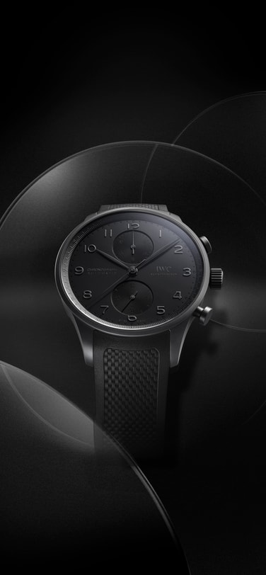 IWC 葡萄牙系列计时腕表 Ceratanium® 置于黑色背景；黑色浮雕表盘搭配纹理黑色橡胶表带。