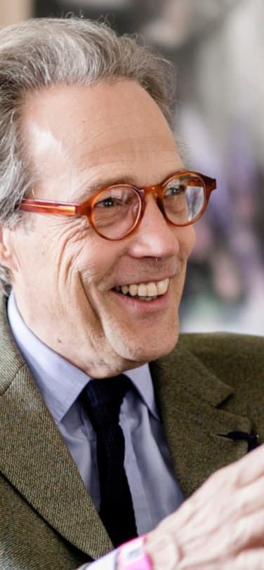 里士满第11世公爵戴着红色眼镜,身穿绿色夹克,面带微笑地坐着在活动中讲话。