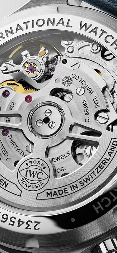 A close-up of the back of an IWC Schaffhausen Pilot's Watch, showing the transparent case back with its automatic mechanical movement.