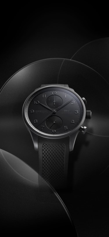 IWC 葡萄牙系列计时腕表 Ceratanium® 置于黑色背景；黑色浮雕表盘搭配纹理黑色橡胶表带。