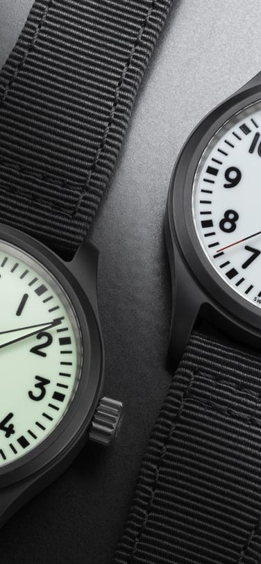 Two Pilot's Watch Automatic 41 Black Aces side by side, the left watch dial is displaying it's glow in the dark functionality
