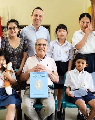 A group photo with children and older adults with the Le Petit Prince book