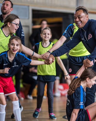 Participants of a Laureus Academy event holding hands together.