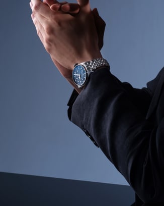 双手交握、手腕上IWC腕表清晰可见的深色西装人物