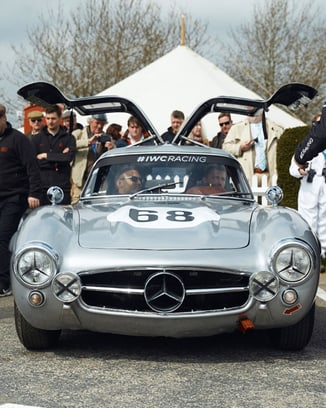 一辆银色梅赛德斯-奔驰300 SL“鸥翼”敞开车门停在古德伍德赛道旁。